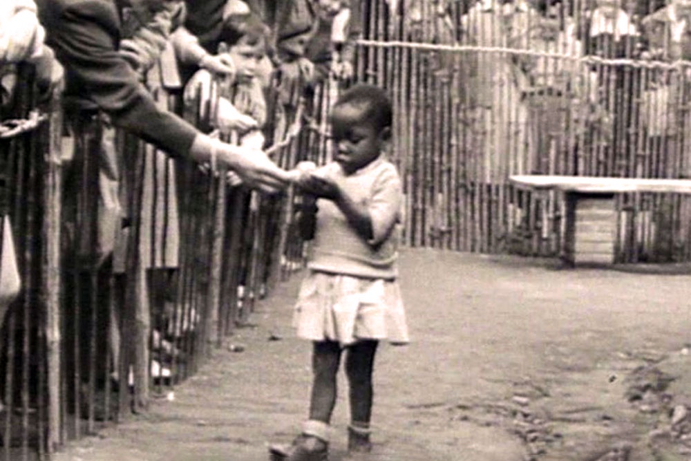 1958 год, добрая посетительница "человеческого зоопарка" в Брюсселе угощает бананом девочку из Конго. / Wikipedia