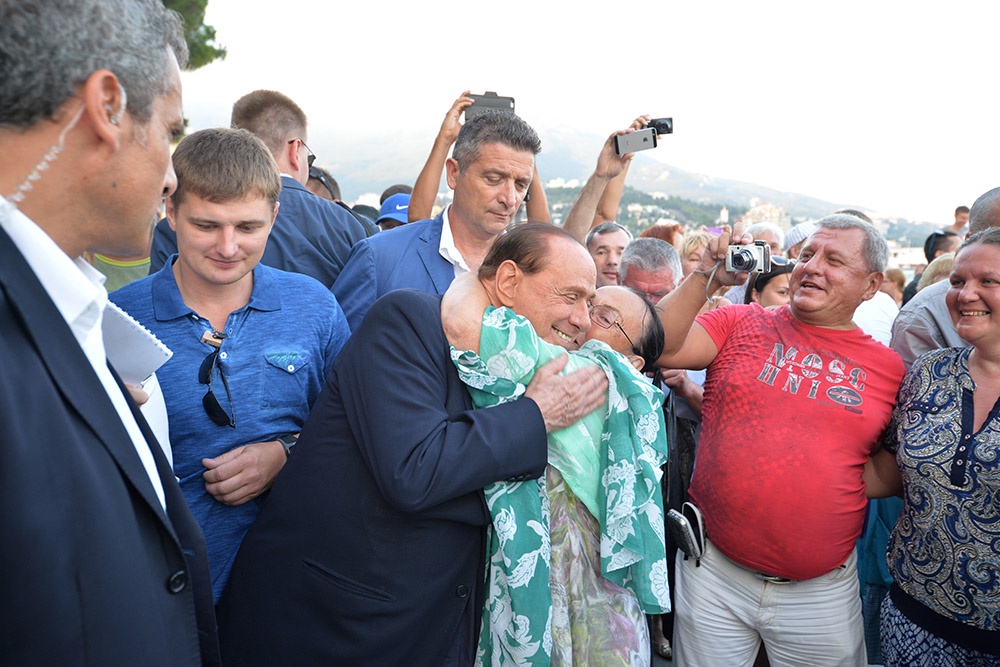 Сильвио Берлускони во время прогулки с российским президентом по ялтинской набережной общается с местными жителями.